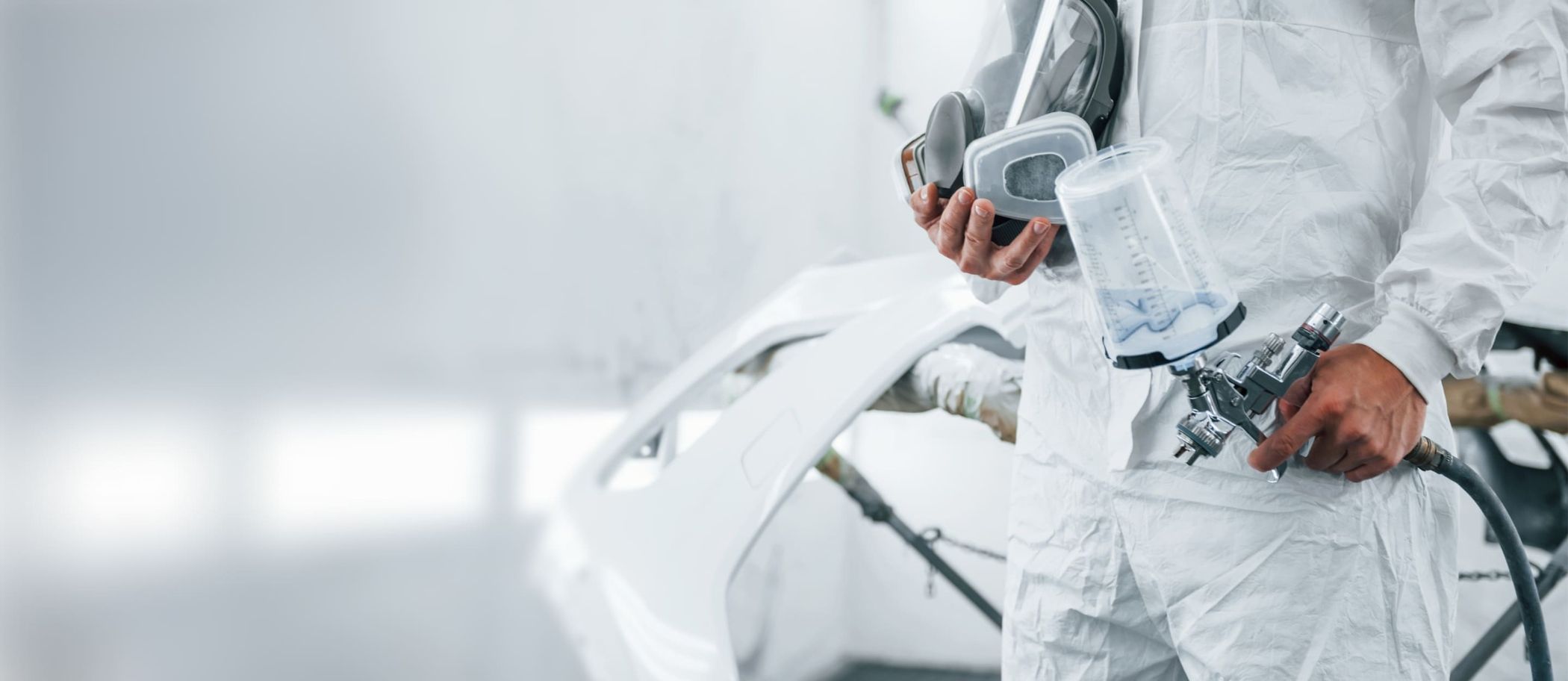 Ein Lackierer hält eine Farbpistole in der Hand